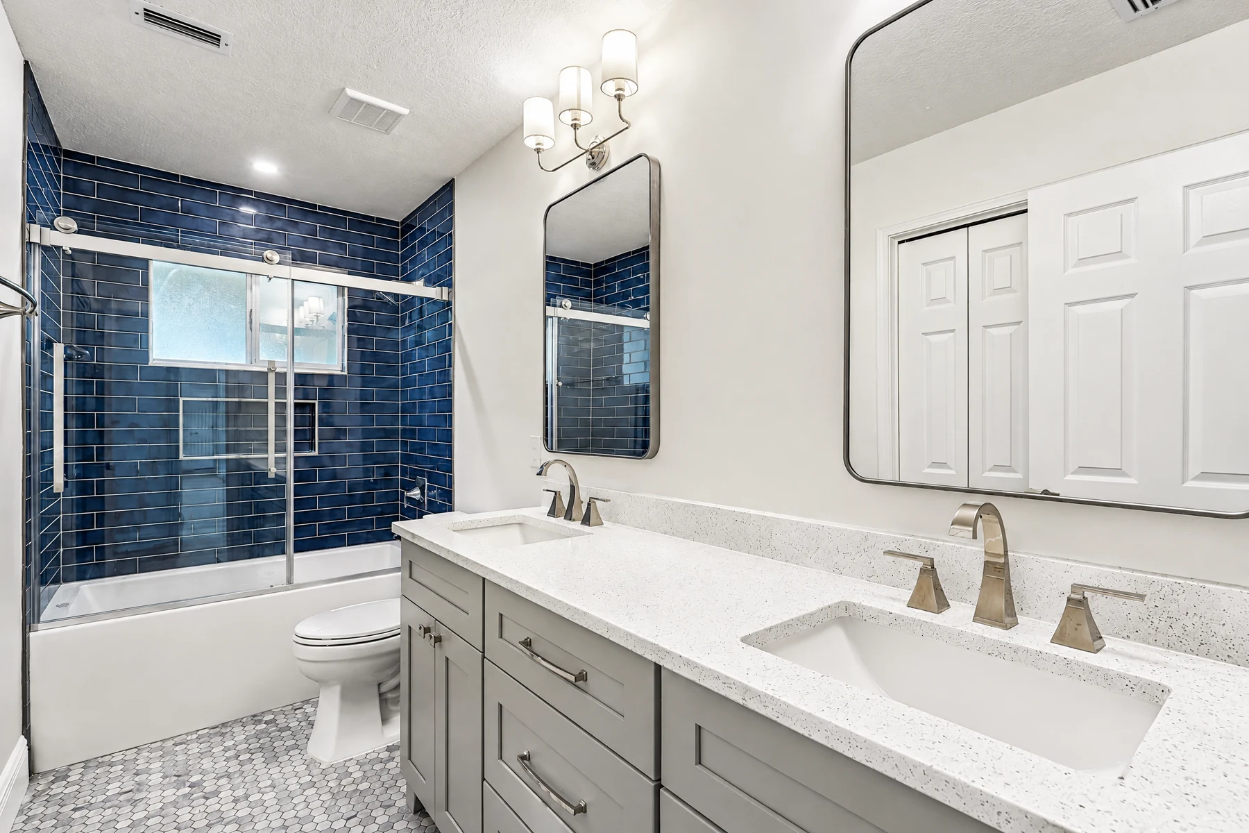 Gray double-sink bathroom vanity with recessed-panel doors, drawers and metal pulls.