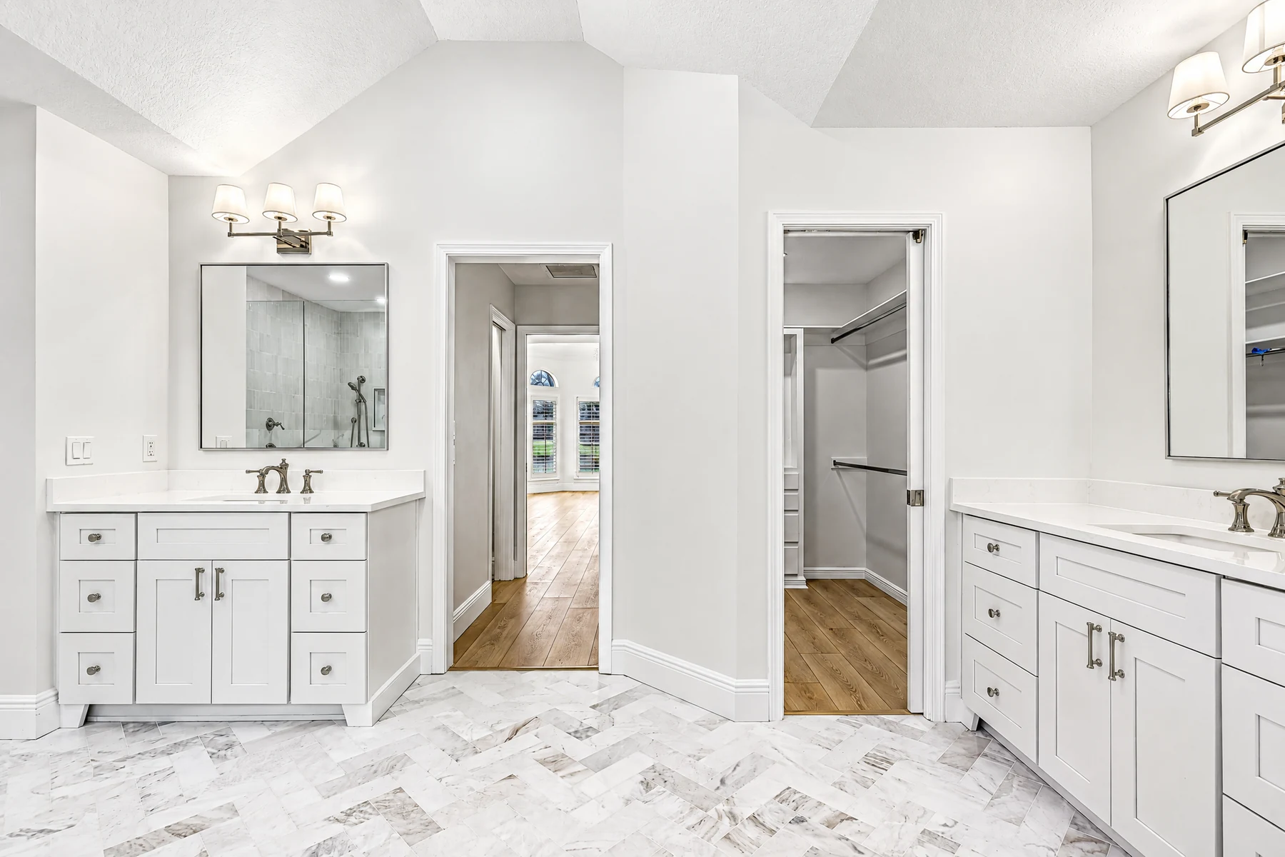 Two white recessed-panel vanity cabinets with drawers and closed storage on opposite sides of a bathroom.