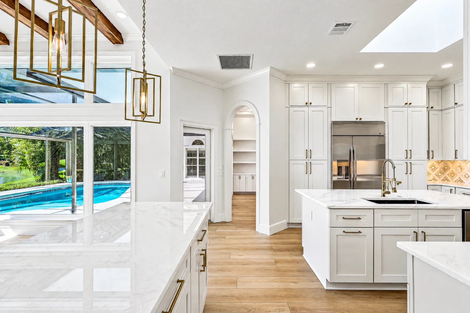 Tall white refrigerator-surround cabinets, island drawers and an arched open-shelf niche.